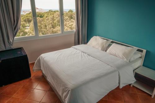 a bedroom with a bed with white sheets and two windows at Sea view malabata family only in Tangier
