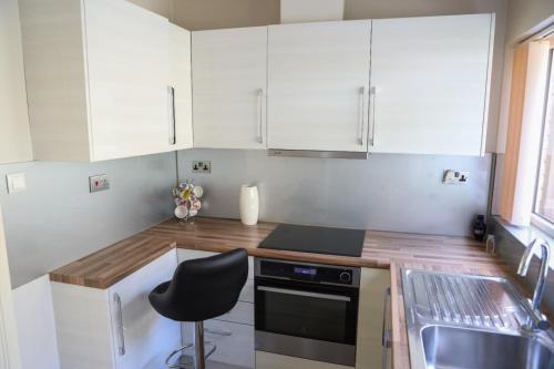 a kitchen with white cabinets and a black chair at CHATHAM GUEST HOUSE in Chatham