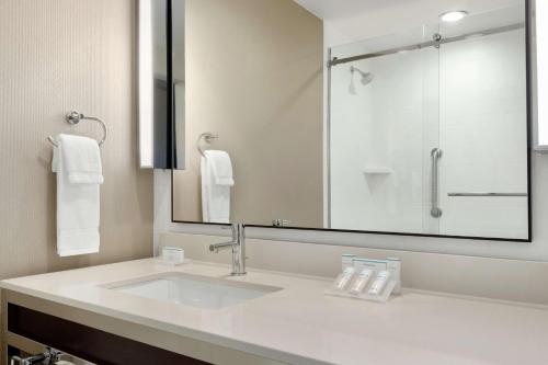 a bathroom with a sink and a large mirror at Hilton Garden Inn Medford in Medford