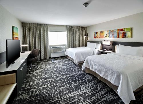 a hotel room with two beds and a flat screen tv at Hilton Garden Inn Roslyn in Roslyn