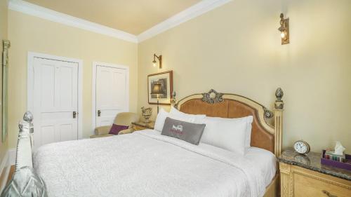 1 dormitorio con cama blanca y reloj en la pared en Grey Gables Inn en Pembroke
