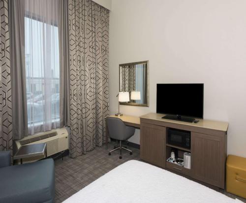 una camera d'albergo con TV e scrivania con sedia di Hampton Inn and Suites Minneapolis University Area, MN a Minneapolis