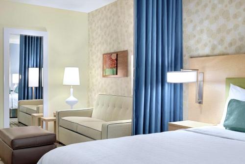 Home2 Suites By Hilton Prattville في براتفيل: غرفه فندقيه بسرير واريكه