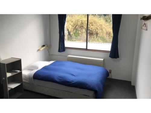 a bedroom with a bed with a blue blanket and a window at Biz Hotel Kiyura - Vacation STAY 93177v in Yura