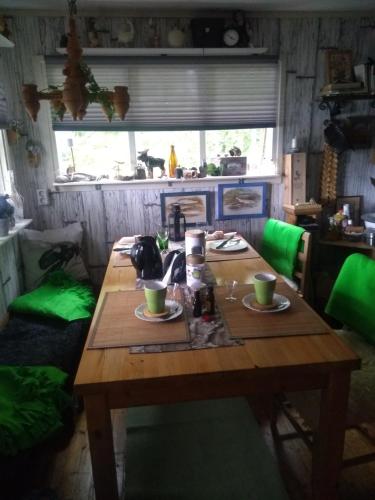 una mesa de madera en una habitación con cojines verdes en Sjöstugan Bodarna Hedemora, en Hedemora