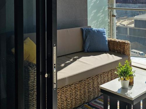 a wicker bench on a balcony with a table at Ellipse Waterfall Luxury Apartments in Midrand