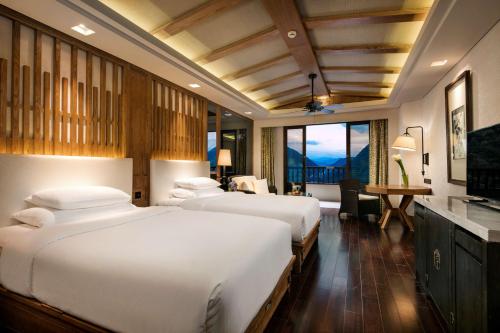 a hotel room with two beds and a desk at Hilton Sanqingshan Resort in Shangrao