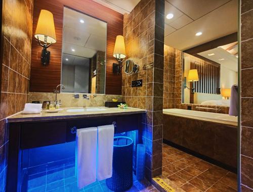 uma casa de banho com um lavatório, uma banheira e um espelho. em Hilton Sanqingshan Resort em Shangrao