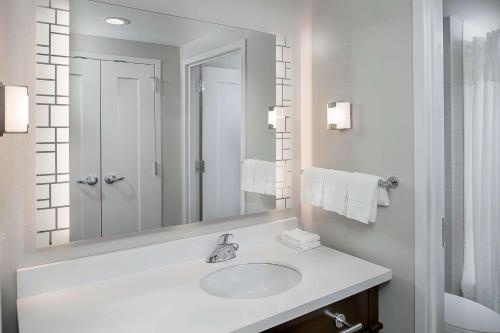 Baño blanco con lavabo y espejo en Homewood Suites by Hilton St. Louis Westport en Maryland Heights