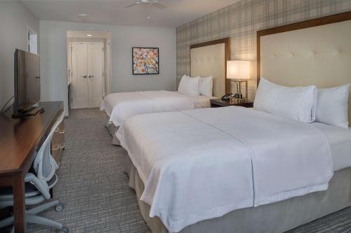 a hotel room with two beds and a television at Homewood Suites by Hilton St. Louis Westport in Maryland Heights