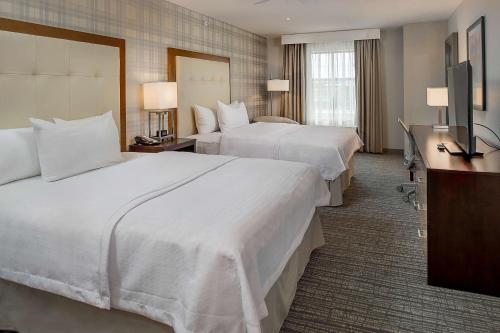 a hotel room with two beds and a flat screen tv at Homewood Suites by Hilton St. Louis Westport in Maryland Heights