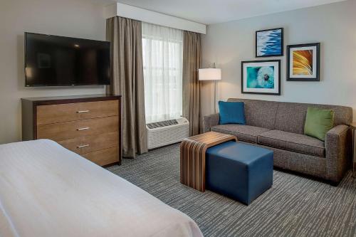 a hotel room with a couch and a tv at Homewood Suites by Hilton St. Louis Westport in Maryland Heights