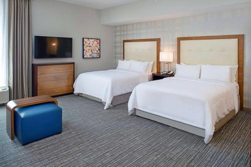 a hotel room with two beds and a blue suitcase at Homewood Suites by Hilton St. Louis Westport in Maryland Heights