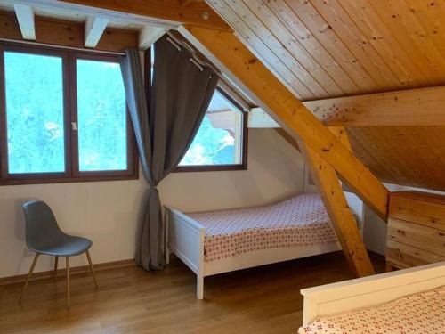 1 dormitorio con 1 cama y 1 silla en el ático en CHALET 16 PERS PROCHE DES PISTES, en Vallouise