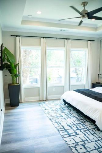 a bedroom with a bed and two large windows at BRAND NEW: Urban Oasis 5 min from Mercedes Benz in Atlanta