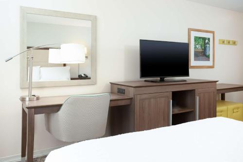 a bedroom with a desk with a television and a mirror at Hampton Inn & Suites Niles/Warren, OH in Niles