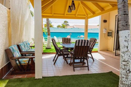 un patio con mesa, sillas y el océano en Blue Sky Residence Aruba en Savaneta