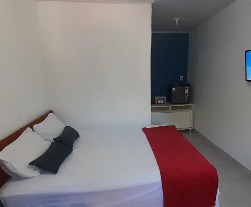 a bedroom with a white bed with a red blanket at Hospedaria Salém in Soure