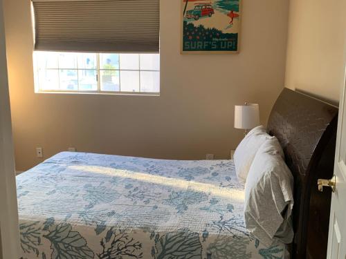 a bedroom with a bed with a blue comforter and a window at Pacific Breeze Right Next to Huntington Beach Pier! Steps from Beach!! in Huntington Beach