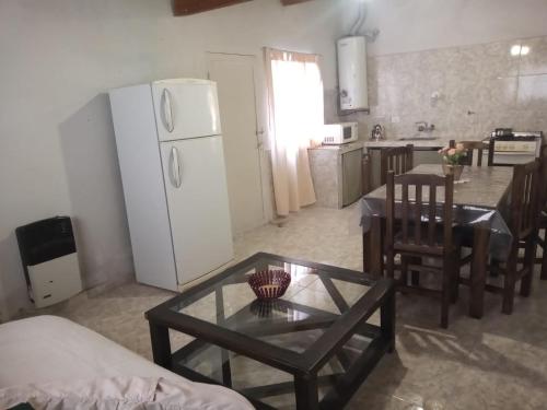uma sala de estar com uma mesa e um frigorífico branco em IAUE EL HOGAR, una habitacion cocina,baño, estacionamiento compartido y patio em Luján de Cuyo