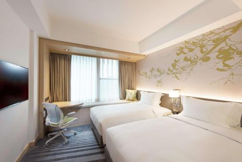a hotel room with two beds and a desk at Hilton Garden Inn Singapore Serangoon in Singapore