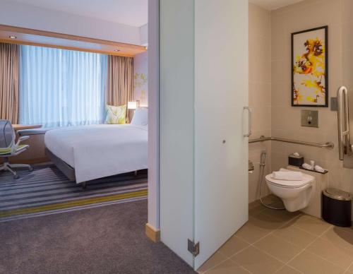 a hotel room with a bed and a toilet at Hilton Garden Inn Singapore Serangoon in Singapore
