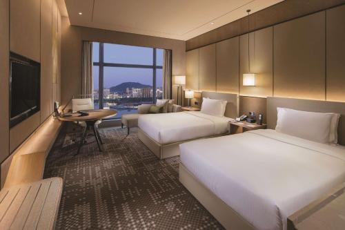 a hotel room with two beds and a television at DoubleTree By Hilton Xiamen-Haicang in Xiamen