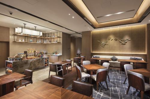 a restaurant with wooden tables and chairs and a bar at DoubleTree By Hilton Xiamen-Haicang in Xiamen
