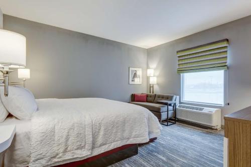 a bedroom with a bed and a couch and a window at Hampton Inn-St. Louis Wentzville, MO in Wentzville