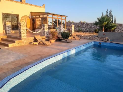 a house with a swimming pool in front of a house at Villa Caroubier in Essaouira
