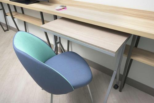 a blue chair sitting next to a desk at Tru By Hilton McDonough in McDonough