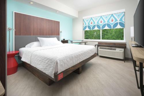 um quarto com uma cama, uma secretária e uma janela em Tru By Hilton McDonough em McDonough