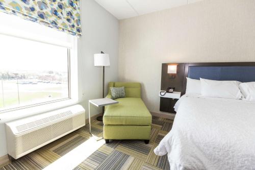 a hotel room with a bed and a chair and a window at Hampton Inn & Suites Syracuse North Airport Area in North Syracuse