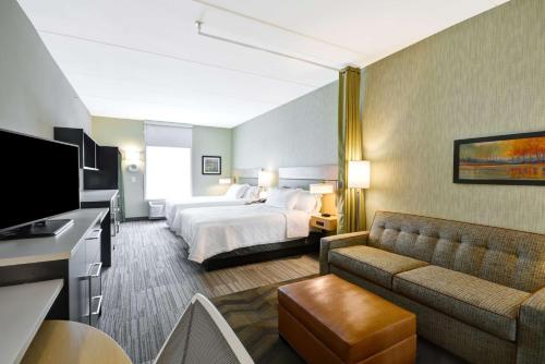 Home2 Suites By Hilton Charles Town في تشارلز تاون: غرفه فندقيه بسرير واريكه