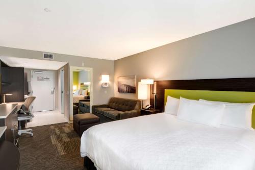 une chambre d'hôtel avec un grand lit et un salon dans l'établissement Home2 Suites Azusa, à Azusa