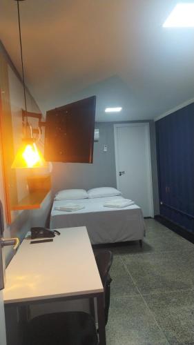 a room with two beds and a table and a desk at Aiezza Hotel in Barcarena
