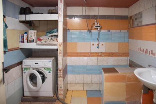 a bathroom with a washing machine and a sink at Horská Roubenka Emma in Čierne