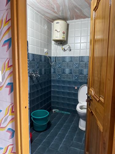 een badkamer met een toilet en een blauwe tegelvloer bij Hotel Maheshwari & Banquet Hall in Chamba
