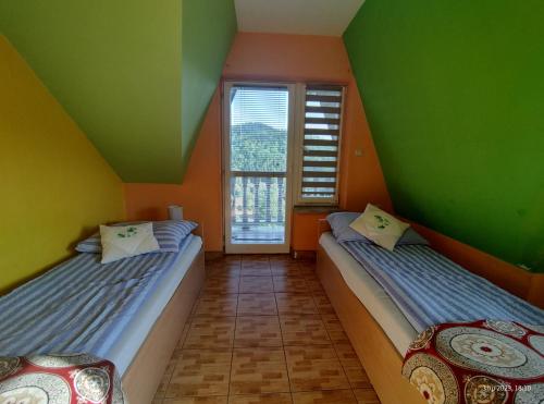 two beds in a room with green and orange walls at Tanie Noclegi Krysia Falsztyn in Falsztyn