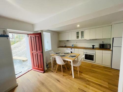 a kitchen with a table and chairs and a red door at Precioso apartamento reformado 2HAB in Elanchove