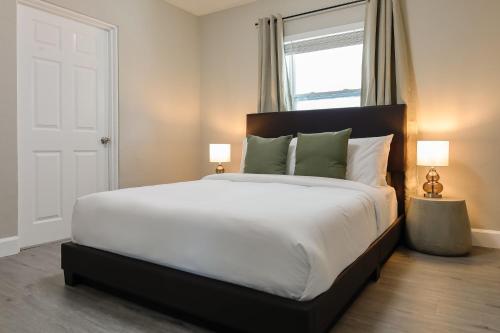 a bedroom with a large bed with white sheets and green pillows at La Vie Boheme 1 - Relaxing Retreat w Parking in Miami