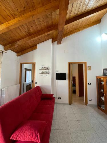 un sofá rojo en una sala de estar con techo de madera en Appartamento tranquillo a due passi dal centro, en Vigevano