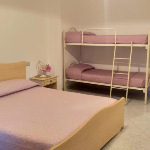 um quarto com 2 beliches com lençóis roxos em Affitto camera il corbezzolo em Palmas Arborea