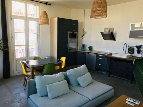un salon avec un canapé et une table dans une cuisine dans l'établissement Appartement climatisé 50m2 une chambre proche centre et gare, à Montpellier