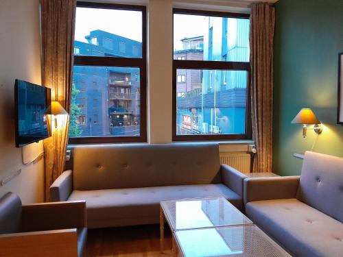 un soggiorno con divano e 2 finestre di Mitt hotell & apartments a Moss