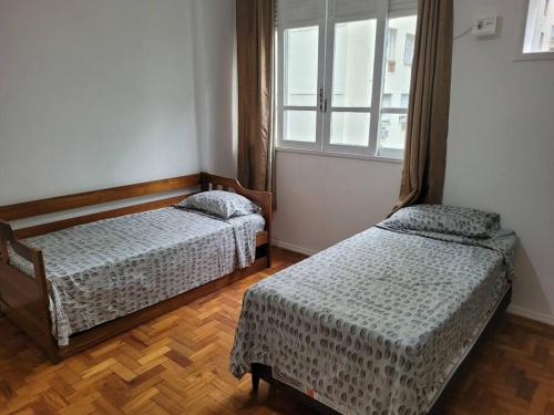 1 Schlafzimmer mit 2 Betten und einem Fenster in der Unterkunft Suhcasa Leme Beach 3 quartos in Rio de Janeiro