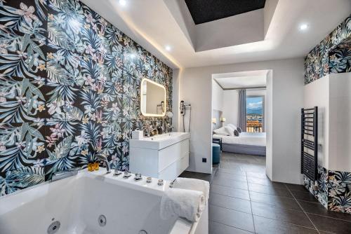 a bathroom with a large tub and a bedroom at Hotel POZZO DI BORGO in Ajaccio