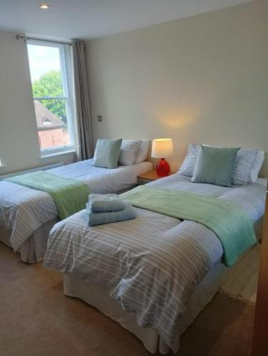 two beds in a room with a window at Executive Barchester House Apartment in Salisbury