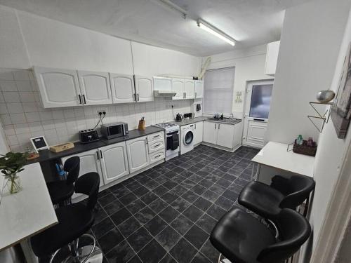 eine Küche mit weißen Schränken und schwarzen Stühlen in der Unterkunft Stylish 2 Bed Apt - Harry Potter/ Leavesden Studios/Watford/Hemel Hempstead - Families/Professionals & Contractors Welcome - Serviced Accomodation in Sarratt