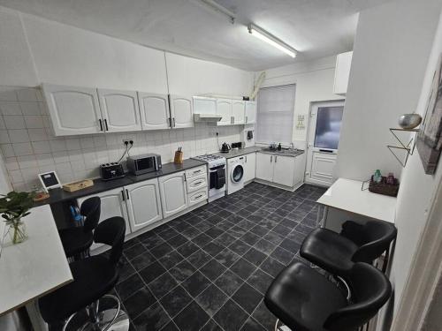 a kitchen with white cabinets and black chairs at Stylish 2 Bed Apt - Harry Potter/ Leavesden Studios/Watford/Hemel Hempstead - Families/Professionals & Contractors Welcome - Serviced Accomodation in Sarratt